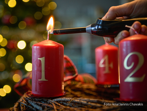 Jemand zündet die Kerzen am Adventskranz an. 