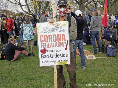 Ein Demonstrant hält ein Schild, auf dem "Corona-Fehlalarm?" steht.