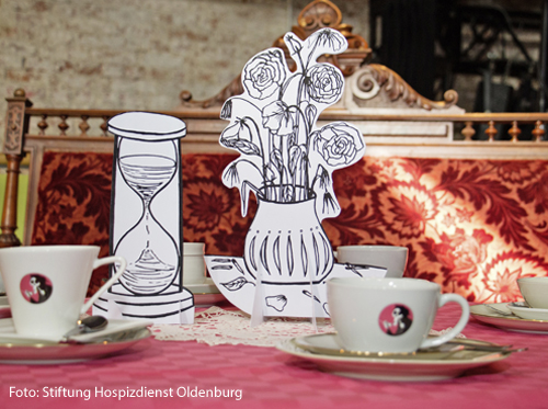 Auf einem Tisch stehen Kaffeetassen und Bilder von Blumenvasen. 