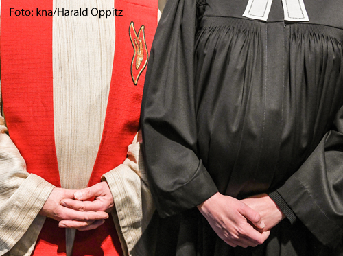 Ein katholischer Priester und ein evangelischer Pastor stehen nebeneinander. 