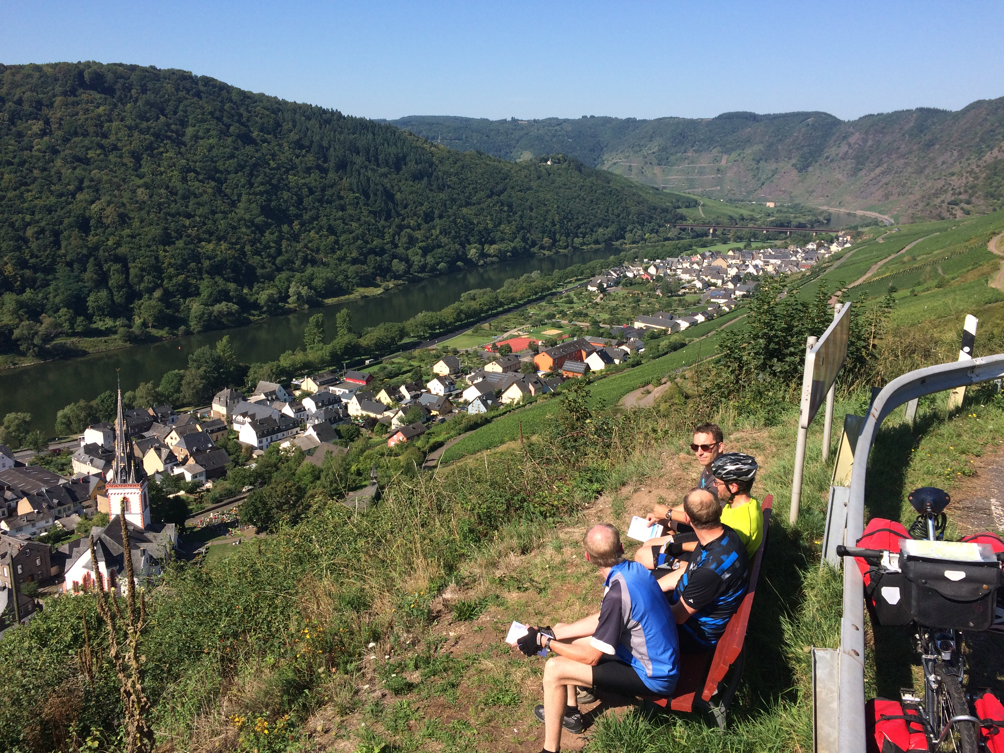 Männer sitzen auf einer Bank und schauen ins Tal.