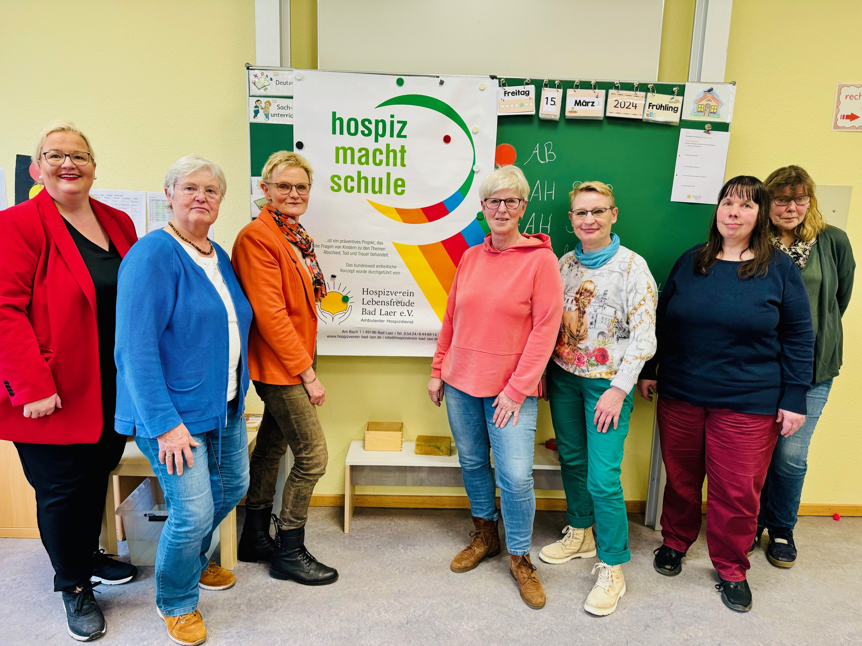 Sieben Frauen stehen vor einem Plakat