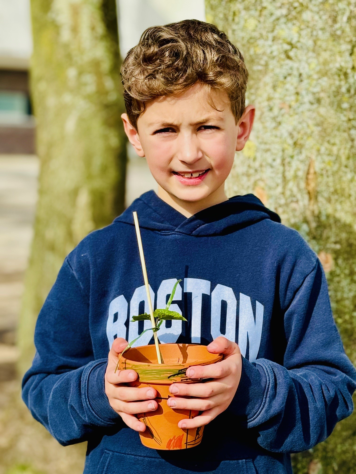 Ein Schüler hält eine Pflanze in einem bemalten Topf in den Händen