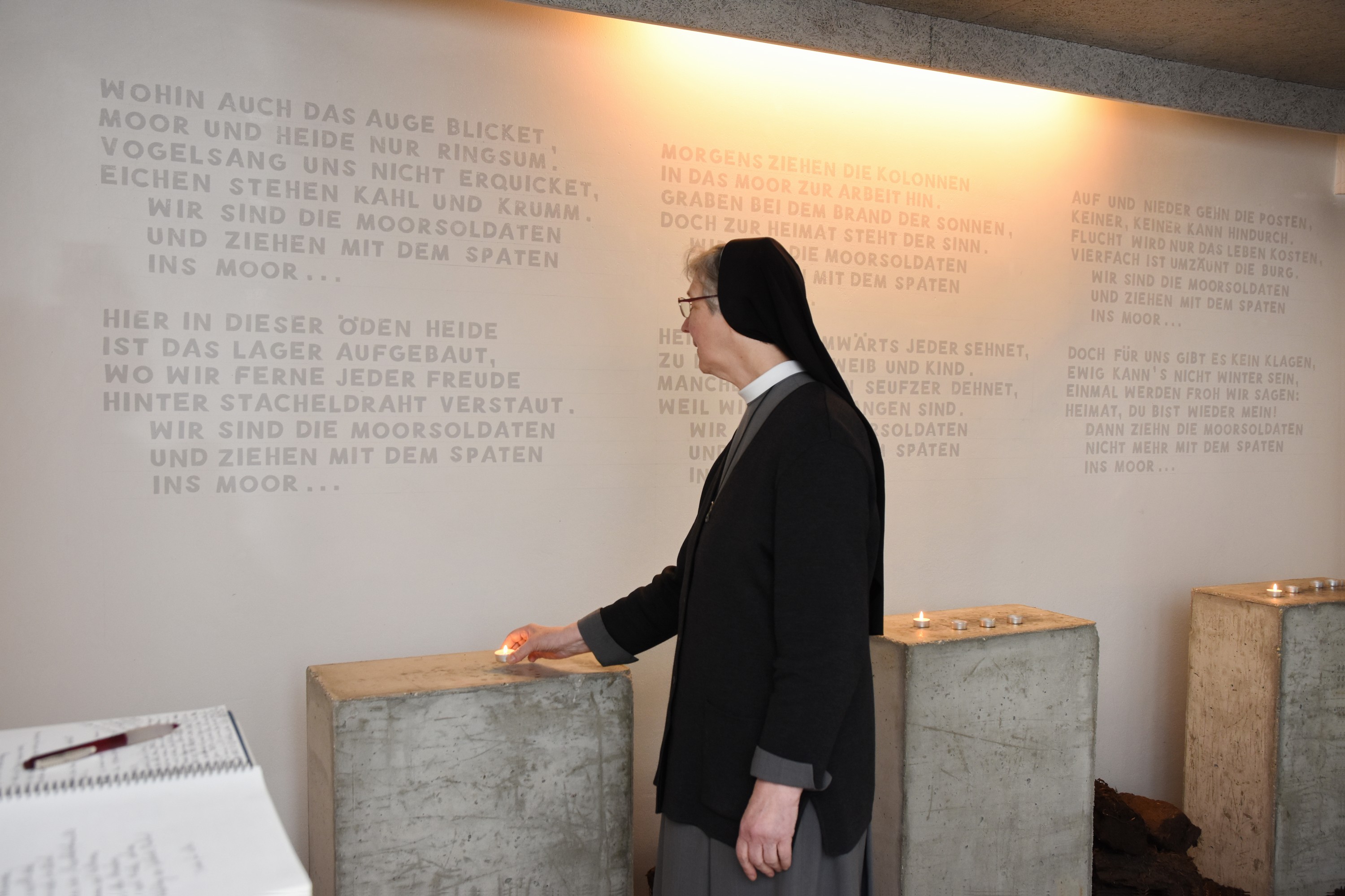 Eine Ordensschwester stellt  eine Kerze auf.