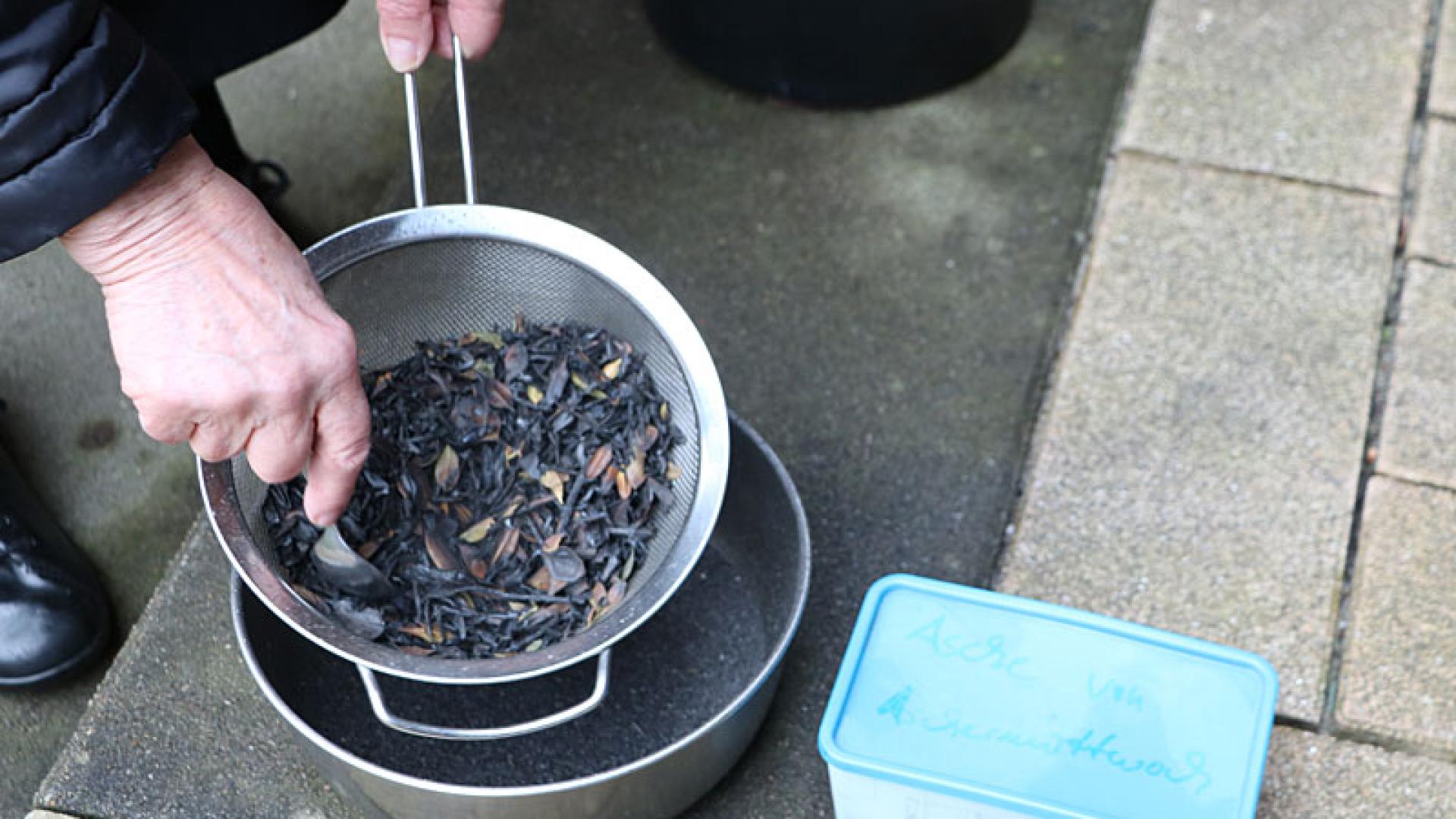 Ordensfrau siebt die verbrannten Buchsbaumzweige zu Asche