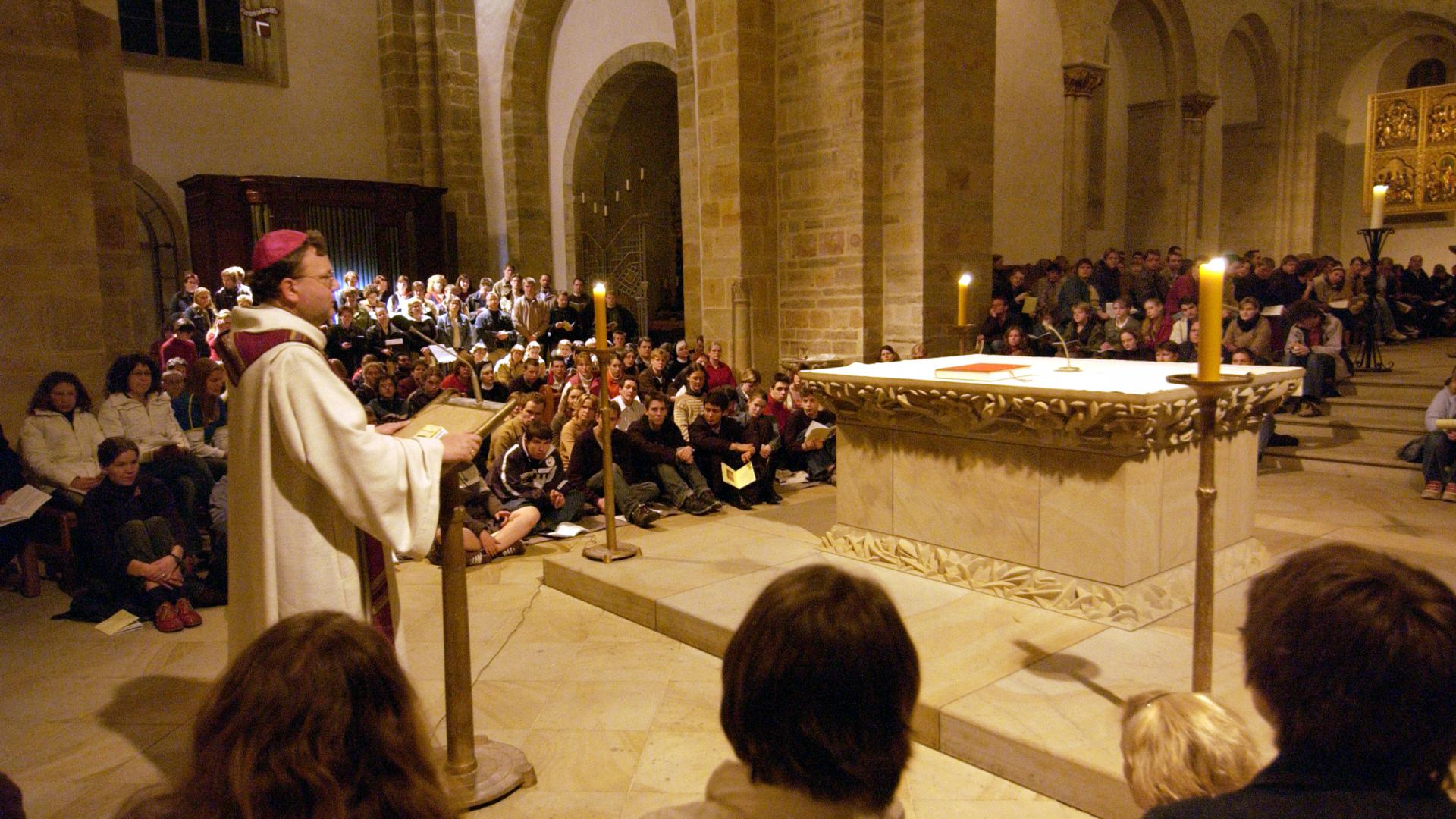 Viele Menschen sitzen im Altarraum einer Kirche