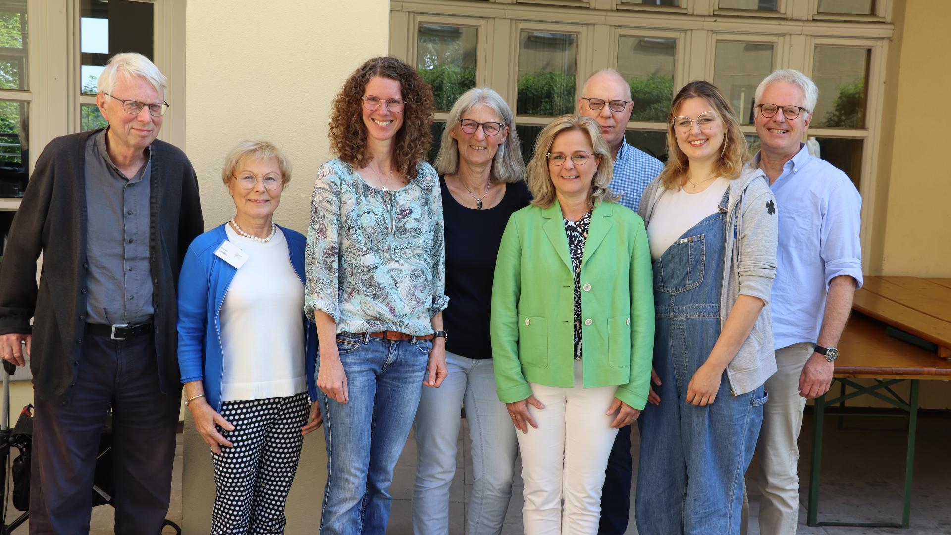 Acht Frauen undMänner stehen vor einer Wand