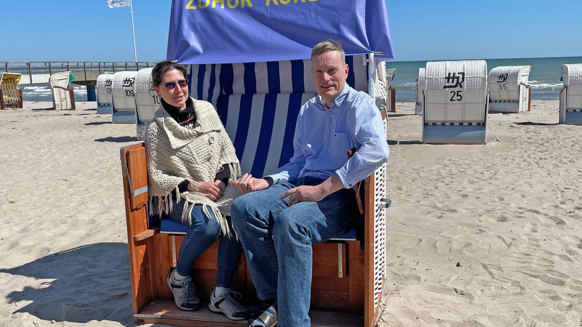 Anna-Maria Janc-Rohr von der Strandkorbvermietung Rohr und Pater Ralf beim Probesitzen im Zuhör-Korb.