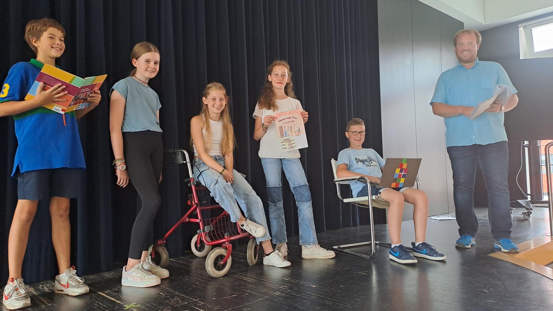 Fünf Schülerinnen und Schüler stehen mit ihrem Lehrer auf einer Bühne.