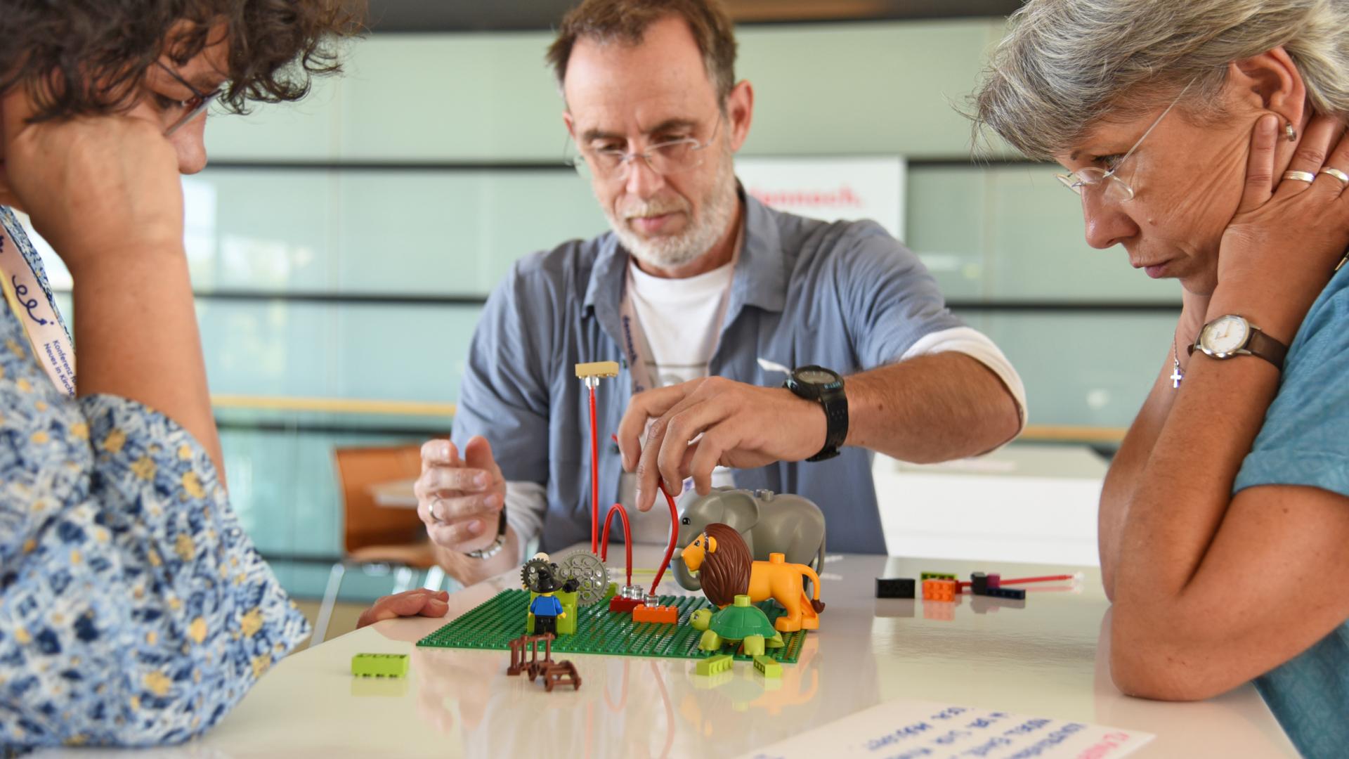 Zwei Frauen und ein Mann denken mit Hilfe von Legosteinen über die Zukunft der Kirche nach