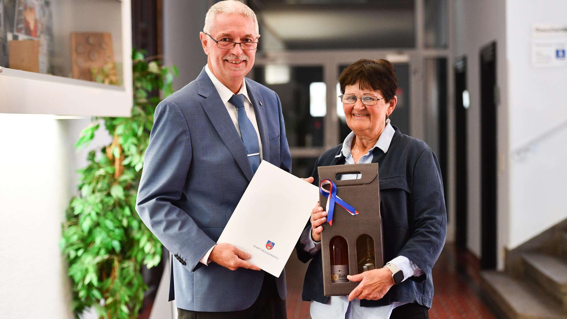 Zwei Senioren halten eine Urkunde in den Händen.