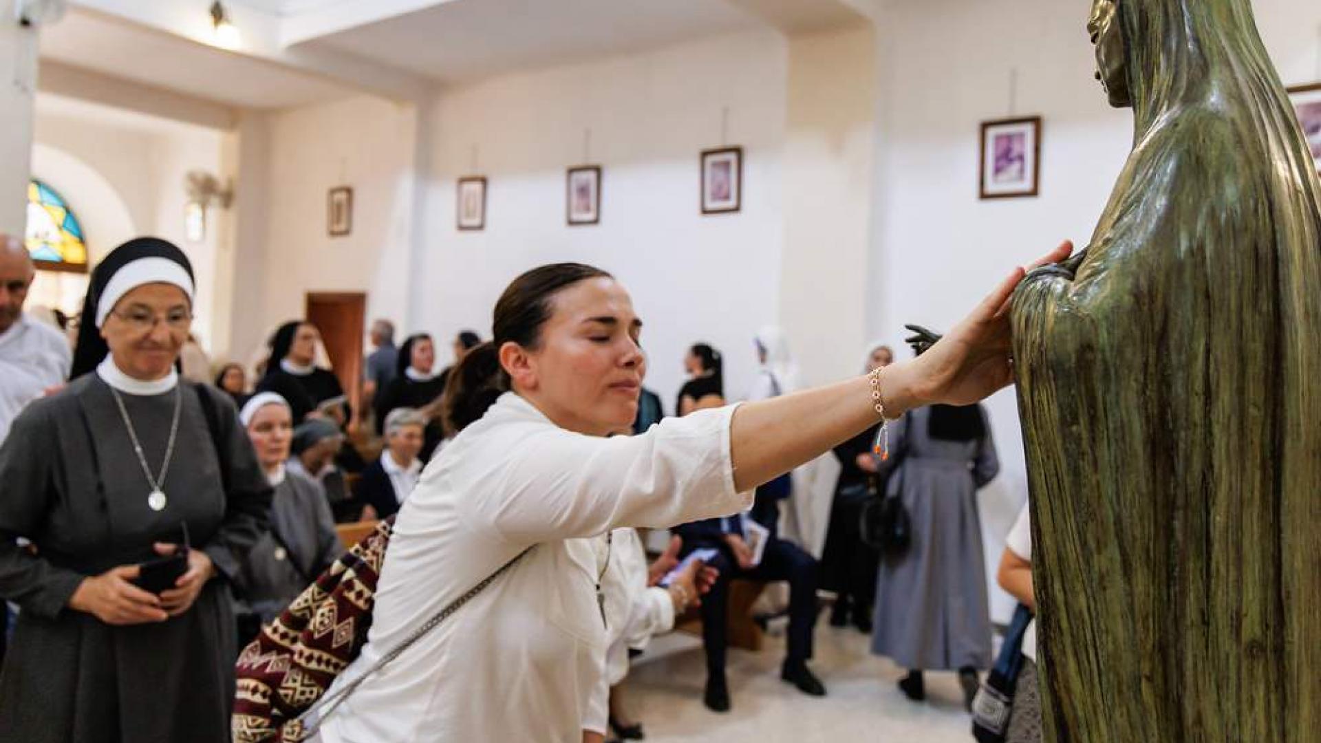 Eine Frau berührt die Marienstatue beim Patronatsfest "Unserer Lieben Frau von Palästina" im Oktober 2023 im Marienwallfahrtsort Deir Rafat (Israel).