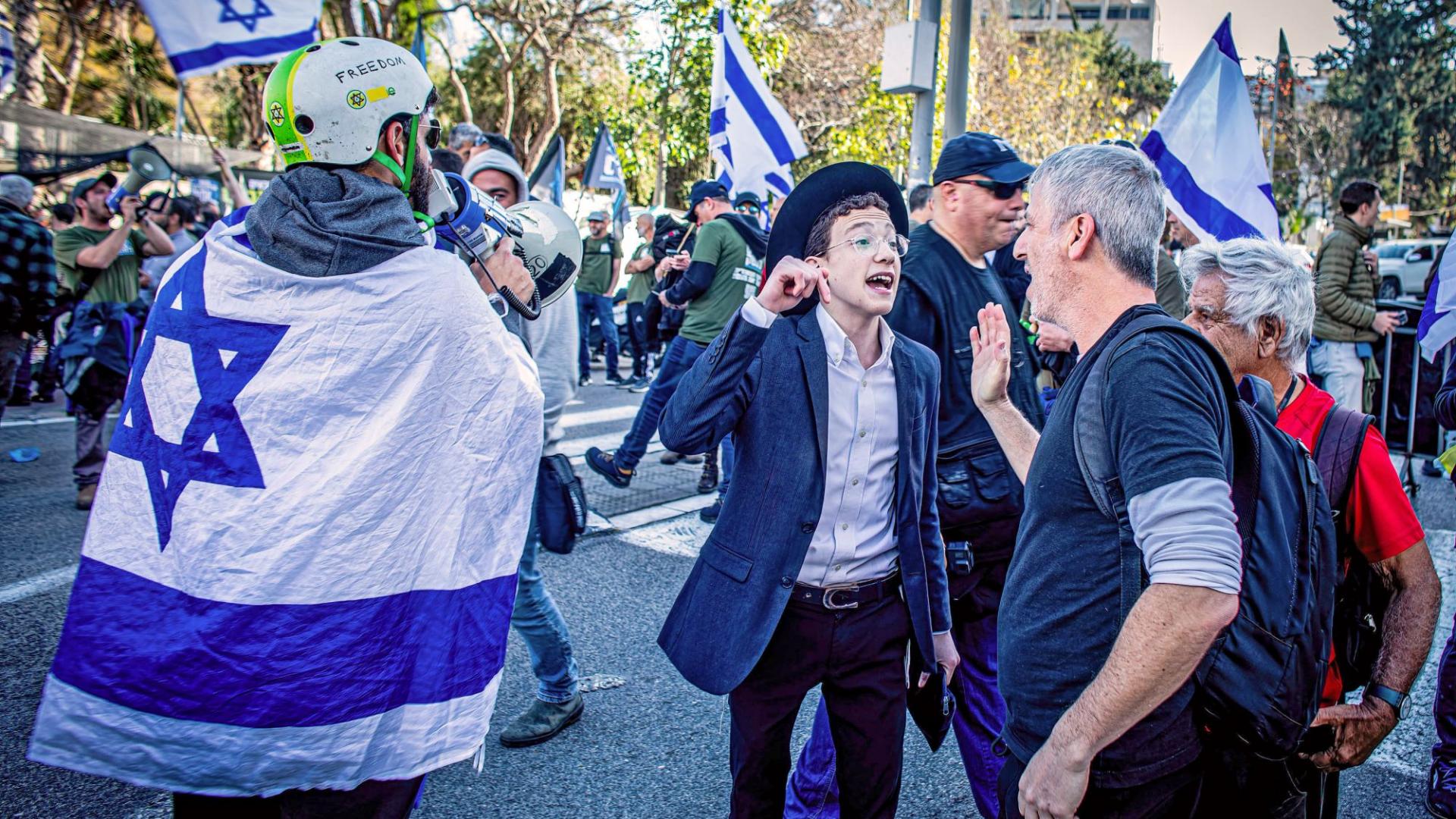 Ein junger Ultra-Orthodoxer diskutiert auf einer Demo lautstark mit einem Reservisten der israelischen Armee, der gegen die umstrittene Justizreform demonstriert
