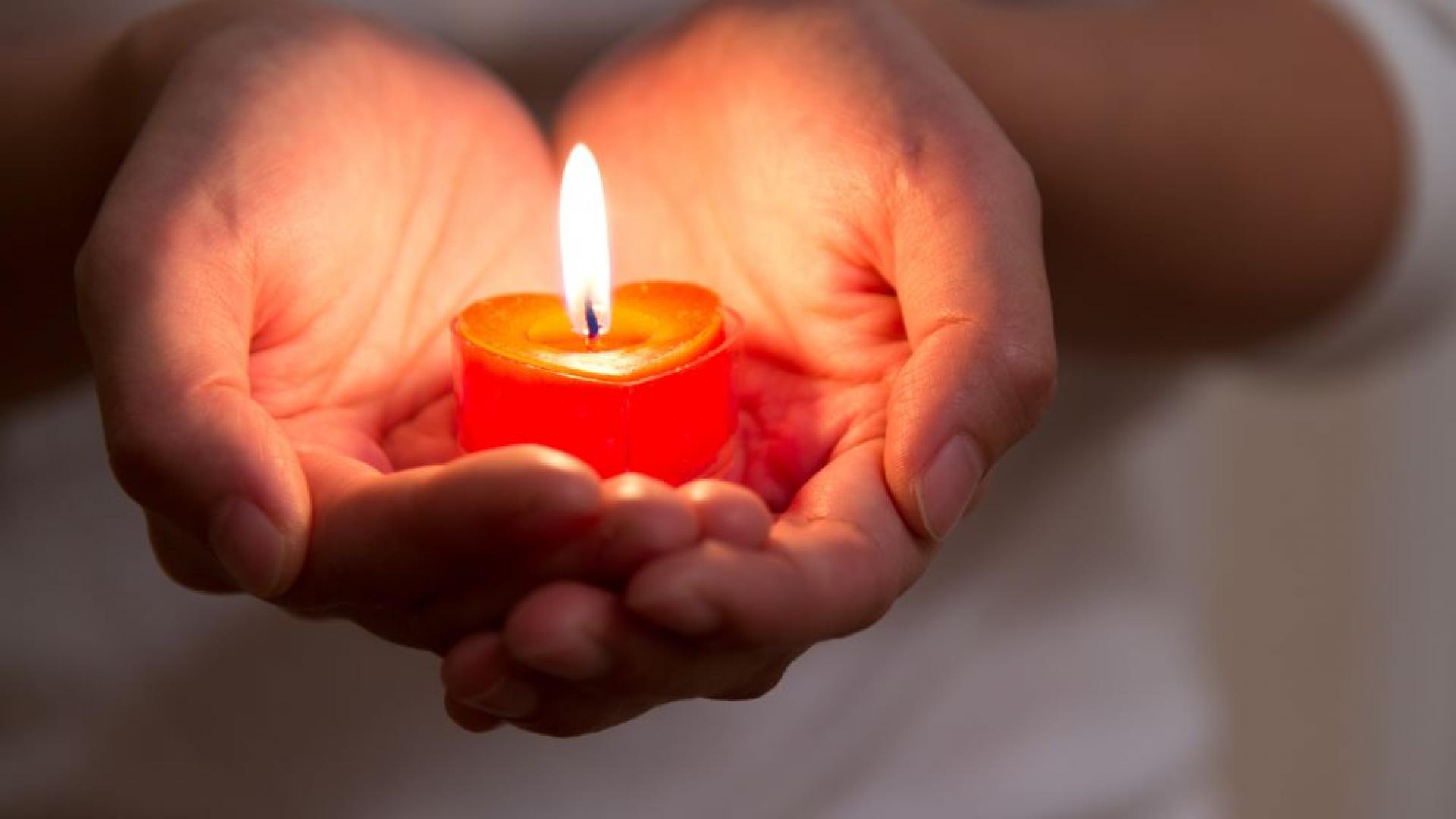 Mann hält ein Kerzenlicht in der Hand