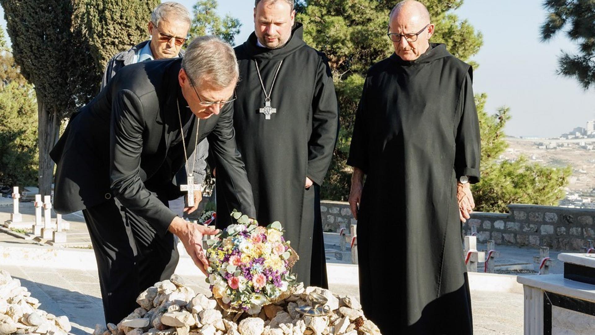 Bischof Heiner Wilmer legt Blumen auf das grab von Oskar Schindler.