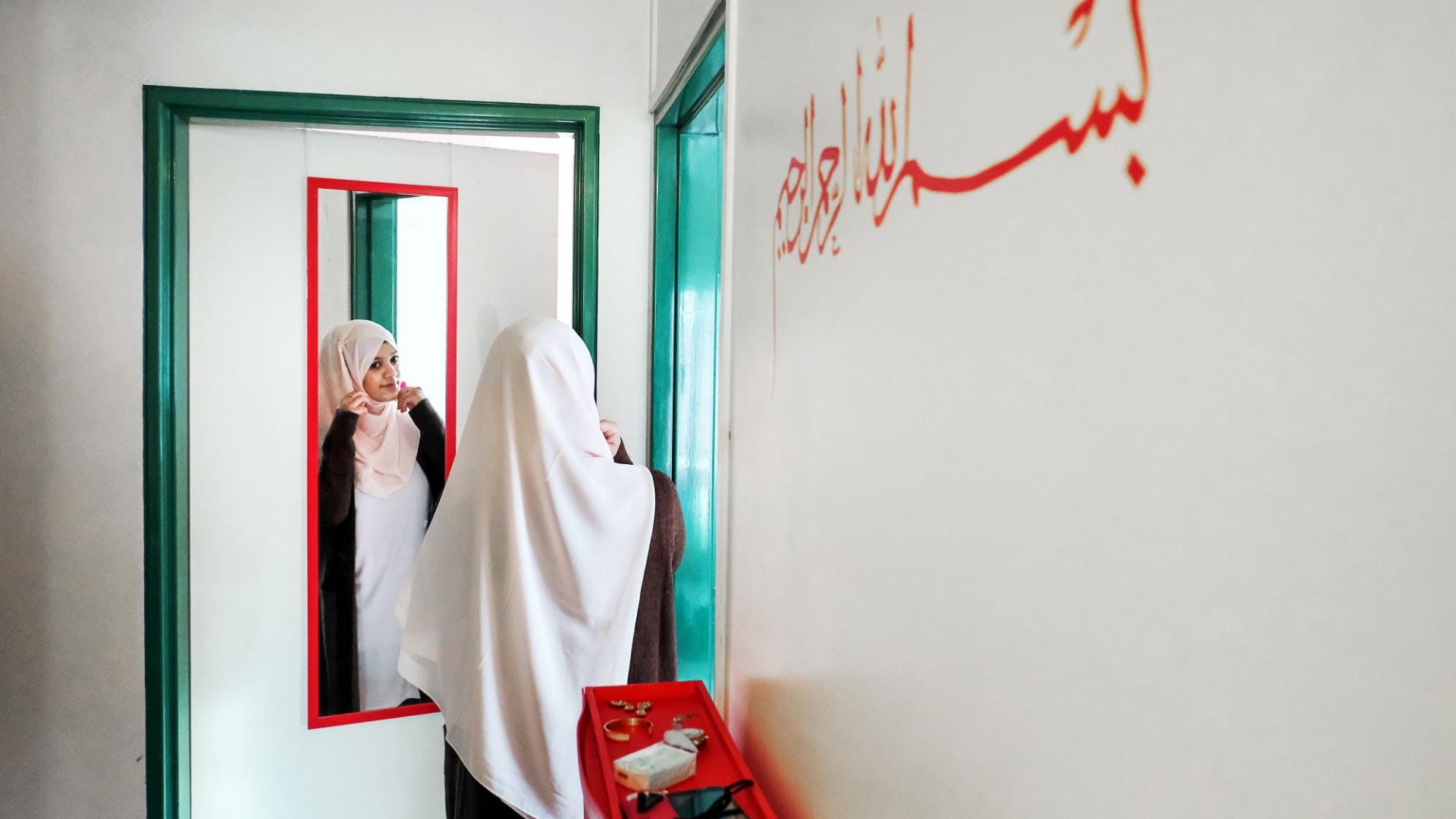 Muslima steht in ihrer Wohnung vor einem Spiegel 