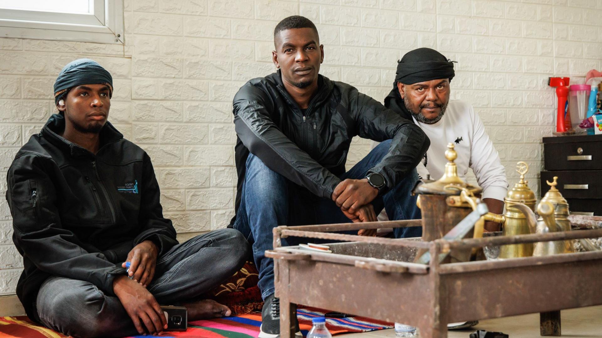 Angehörige einer Beduinenfamilie sitzen auf dem Boden