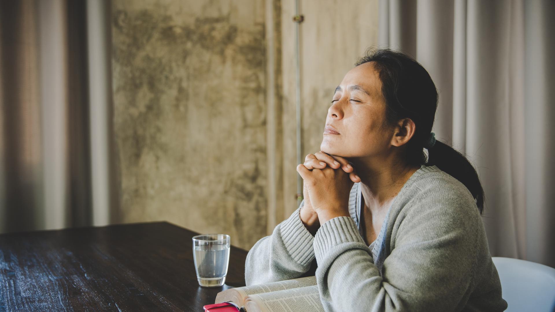 Frau mit geschlossenen Augen hat Hände gefaltet
