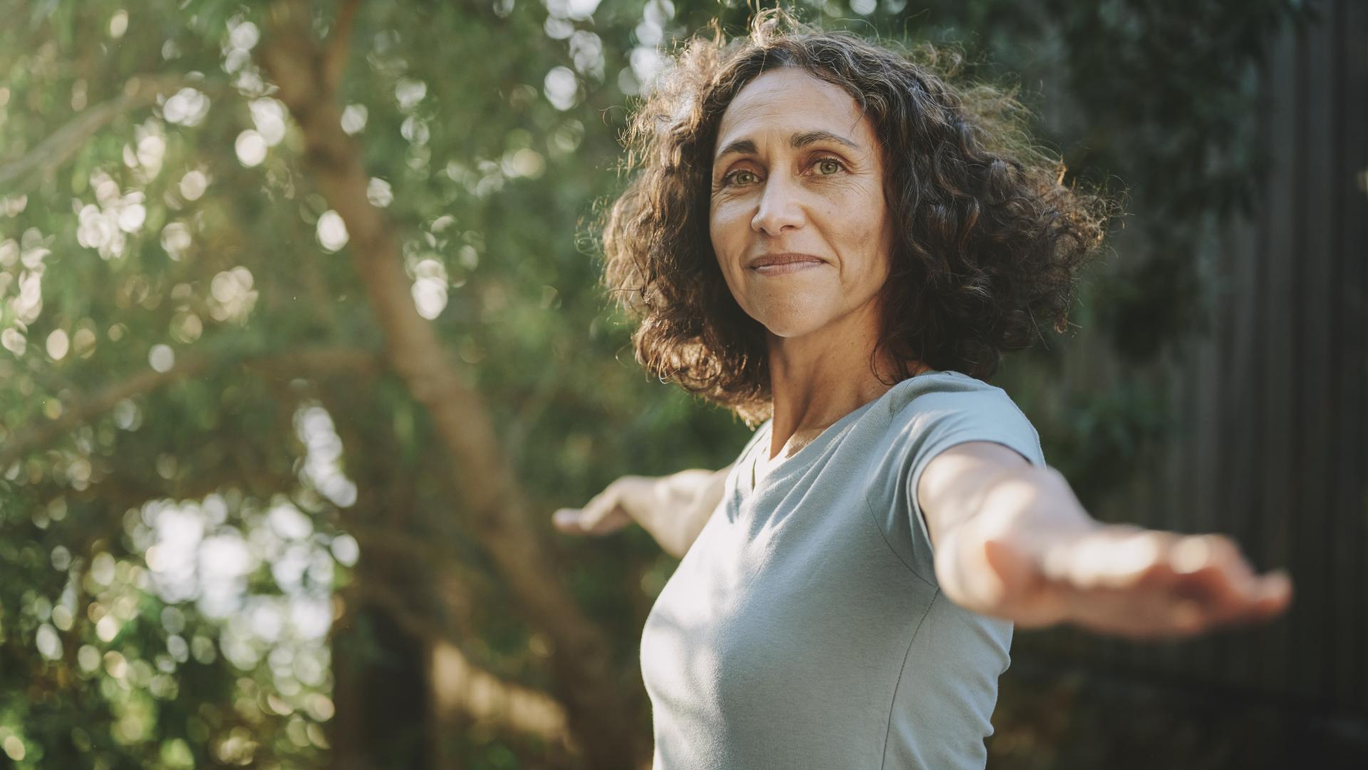 Eine zufrieden aussehende Frau übt die Yogapose Kriegerin.