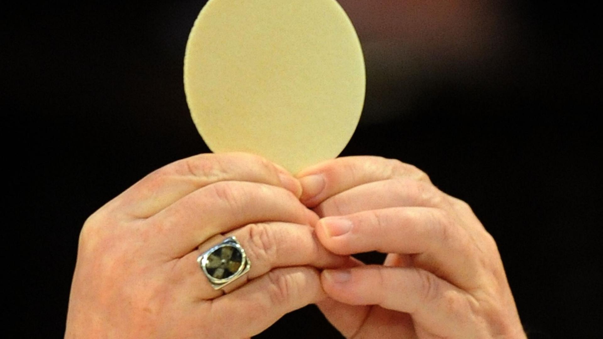 Ein Priester hält die Hostie hoch