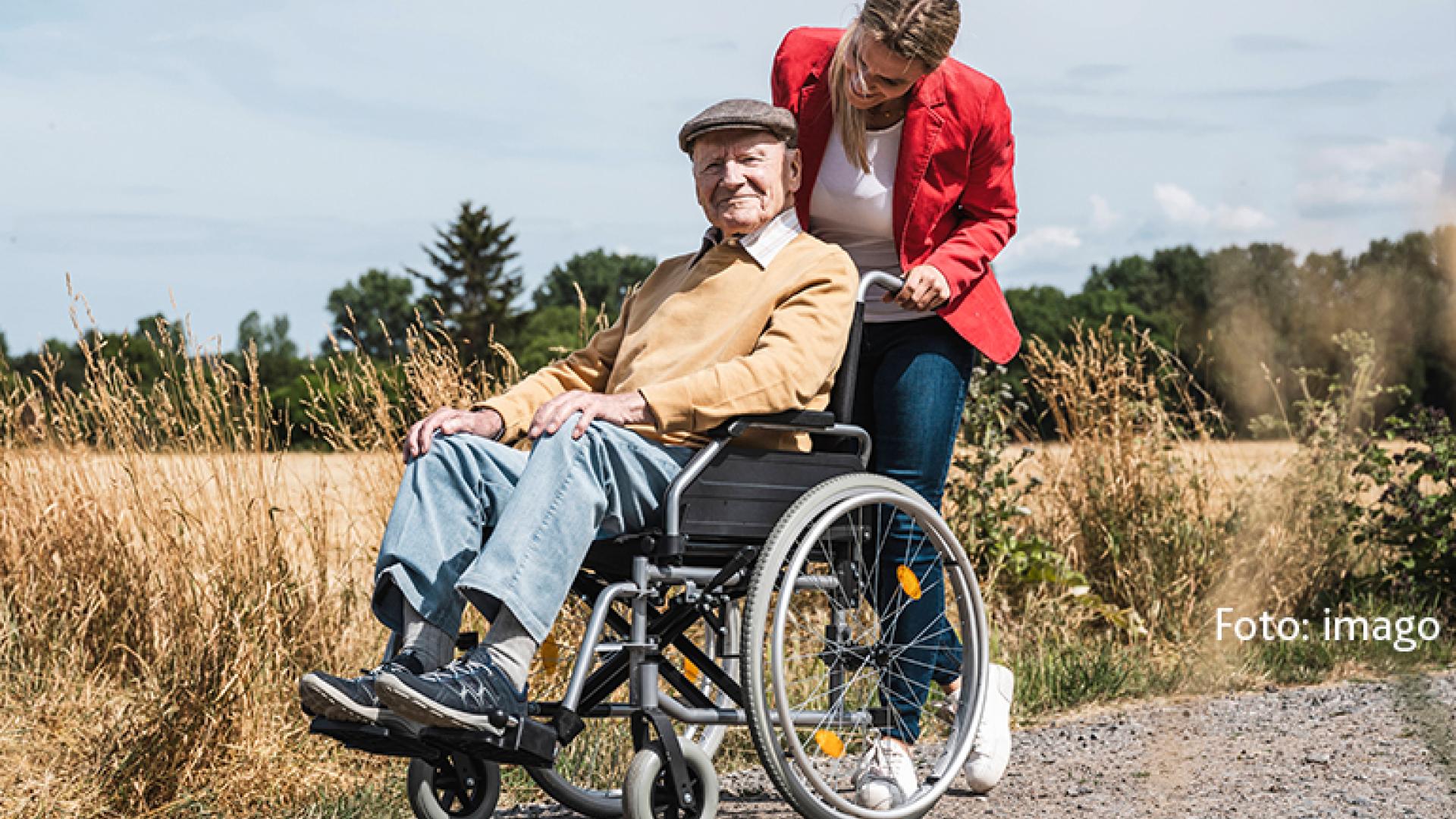 Rollstuhlfahrer und Helferin beim Spazieren