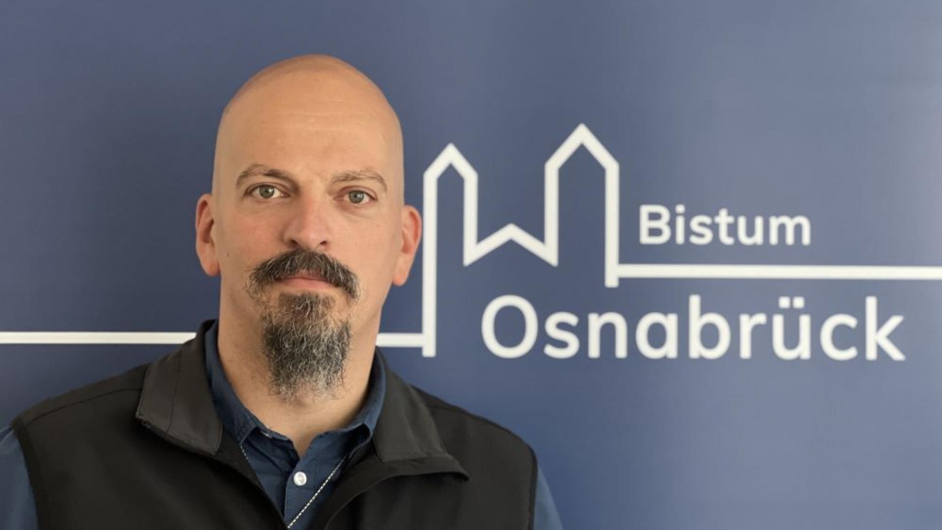 Jens Kuthe vor dem Bistumslogo