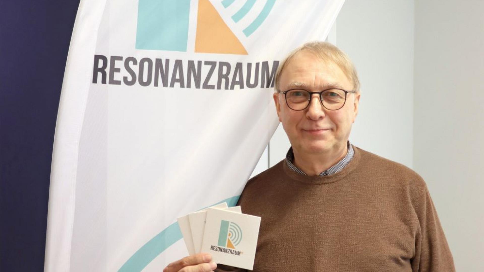 Martin Bruns vor dem neuen Logo des Angebots Resonanzraum