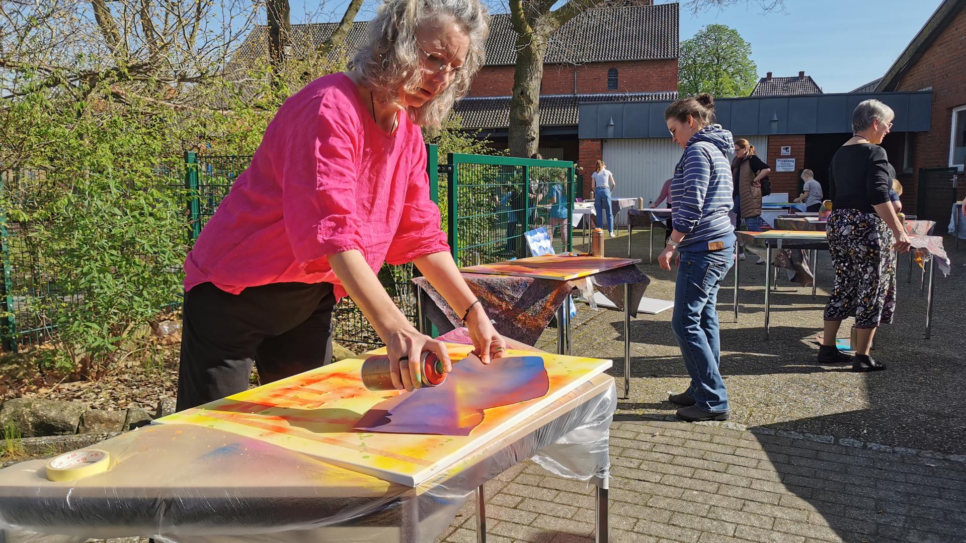 Eine Frau sprüht mit bunten Farben ein Bild.