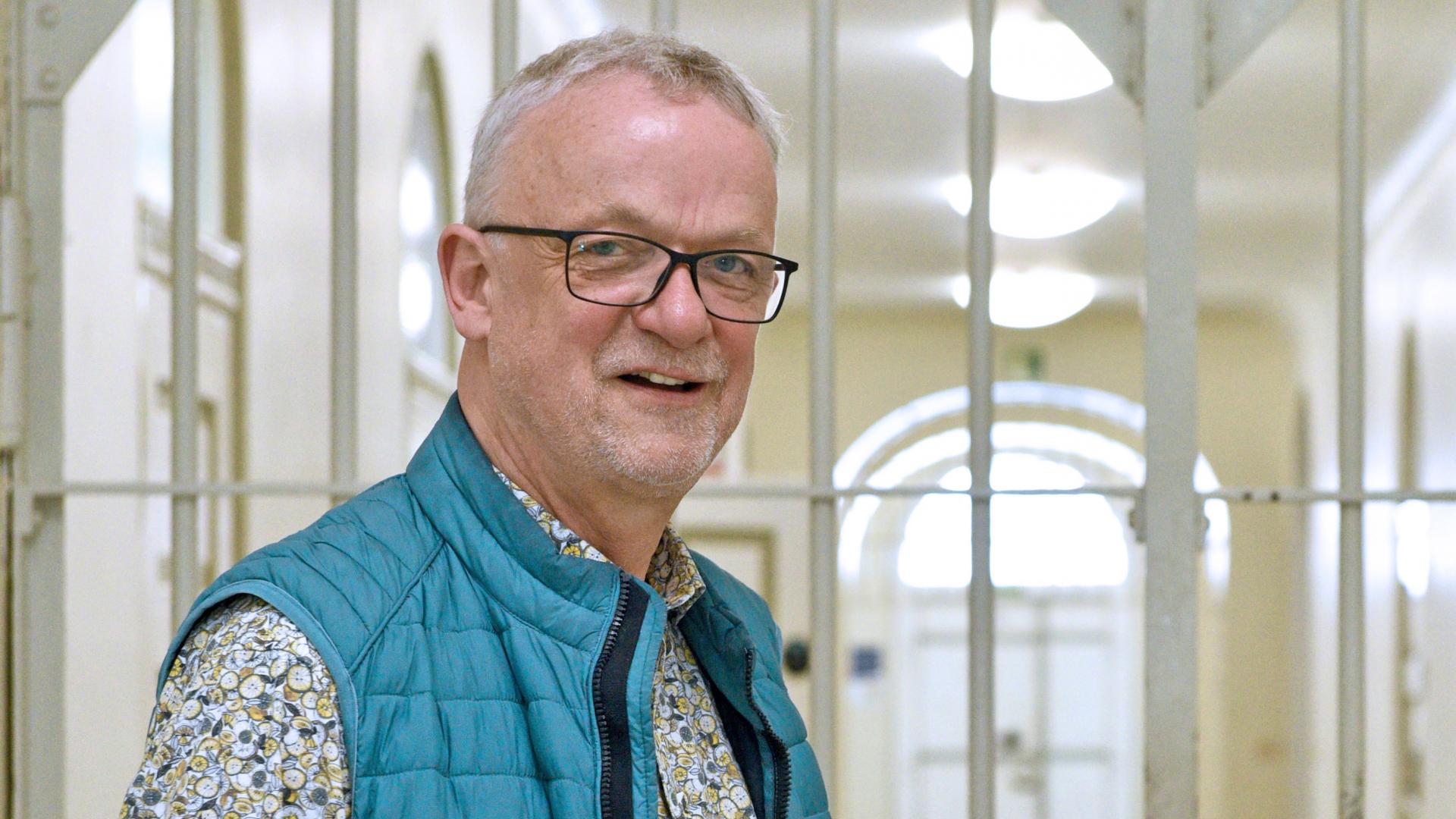 Mann steht vor einer Gittertür.